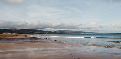 a sandy beach with lapping waves against a heavy cloudy sky 