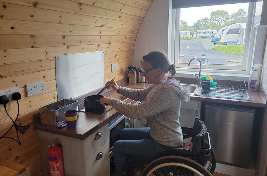 A woman in a wheelchair skillfully prepares a meal in a modern kitchen