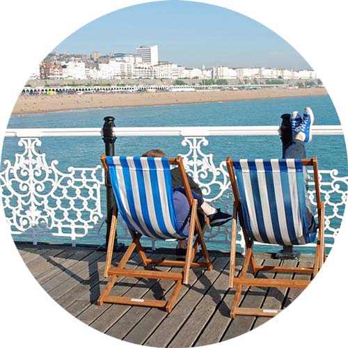 Couple sitting on deck chairs on Brighton Pier, East Sussex