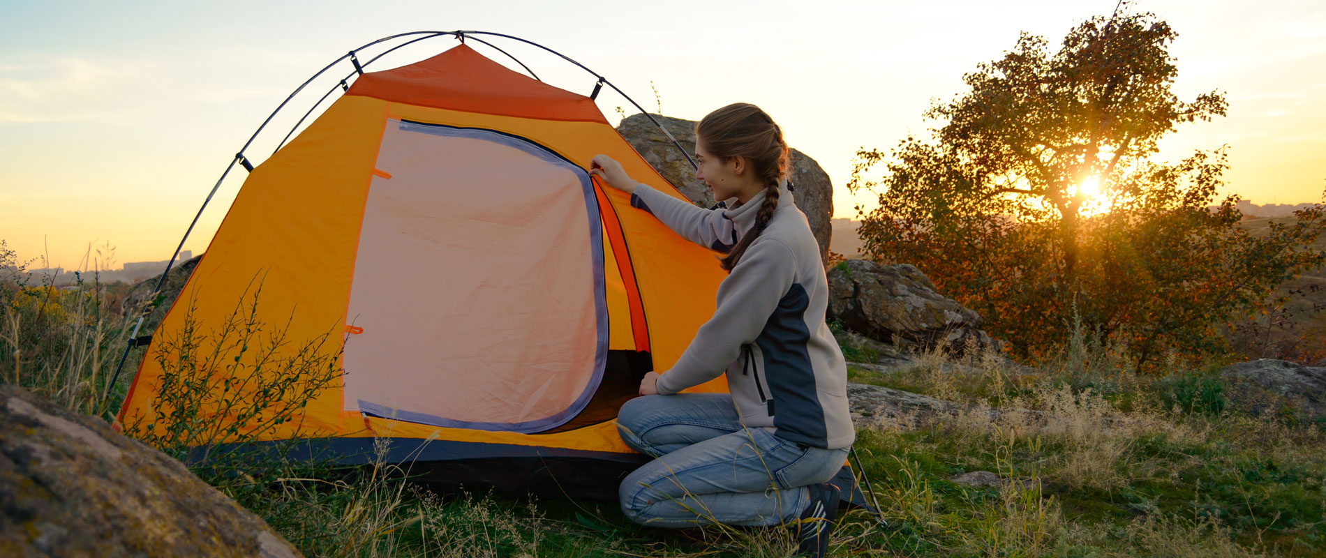 Girl putting up a tent surrounded by nature