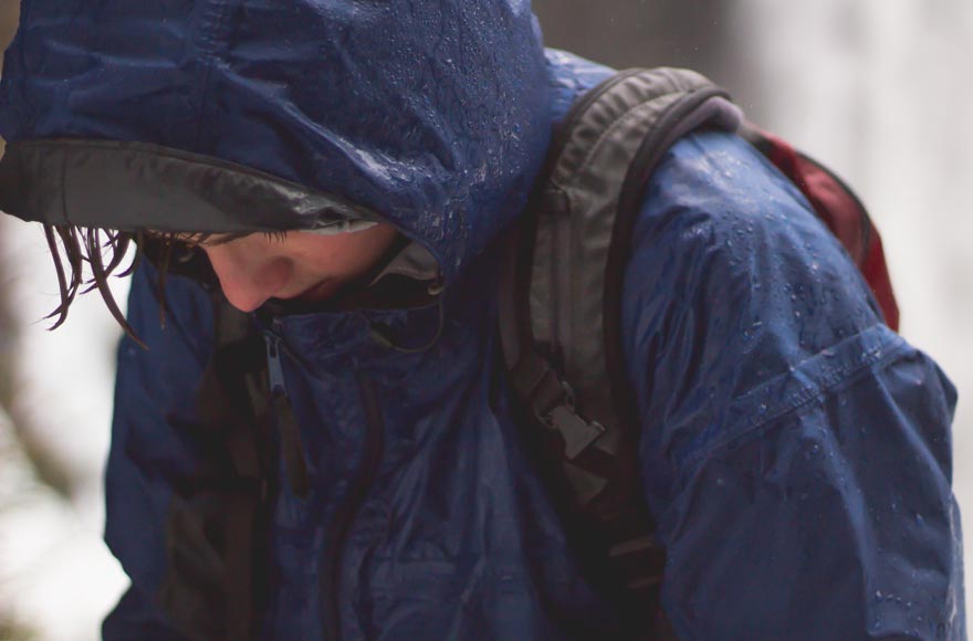 Boy in raincoat wearing backpack in downpour